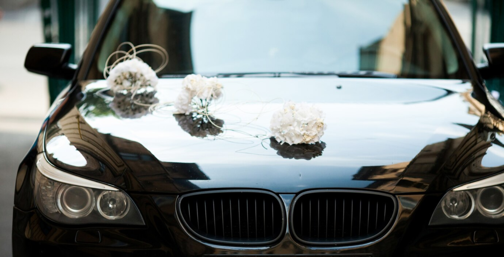 Bride and groom stepping out of a white luxury BMW decorated with flowers at a wedding venue in Lucknow, symbolizing luxury car booking for marriage and VIP events for a stylish grand entry.